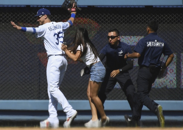 Los Angeles Dodgers right fielder Cody Bellinger is rushed by a fan on the field at Dodger Stadium